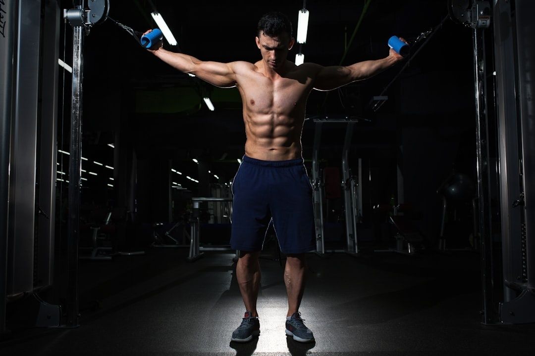 Man tränar bröst med kabelmaskin på ett mörkt gym