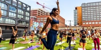 Utomhuspass med instruktör och deltagare på yogamattor i en stadsmiljö