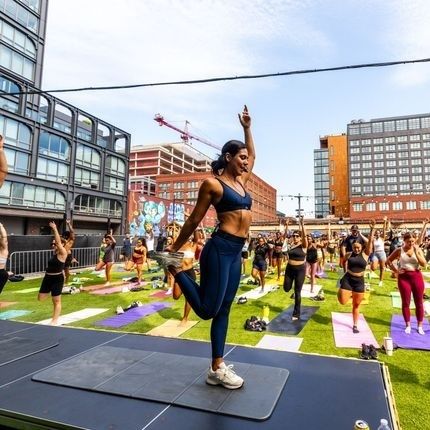 Utomhuspass med instruktör och deltagare på yogamattor i en stadsmiljö
